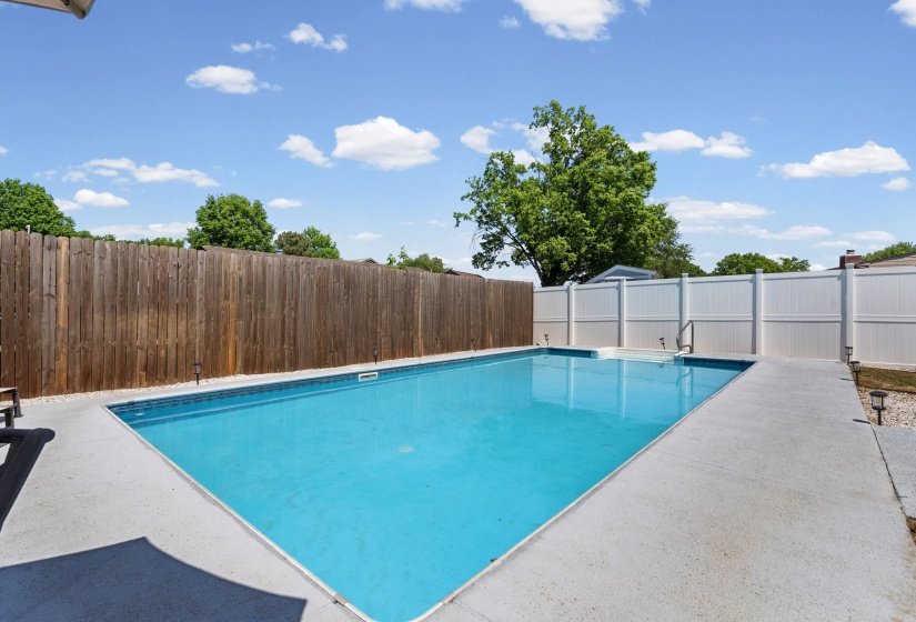 In-ground swimming pool with an integrated shallow sun shelf, surrounded by a concrete deck