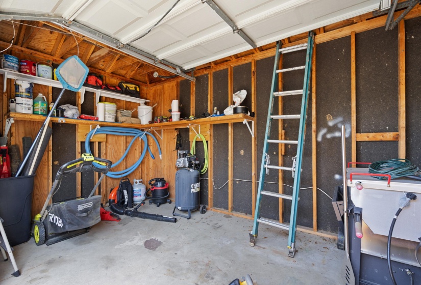 Garage interior featuring wood framing, exposed insulation, and a concrete floor