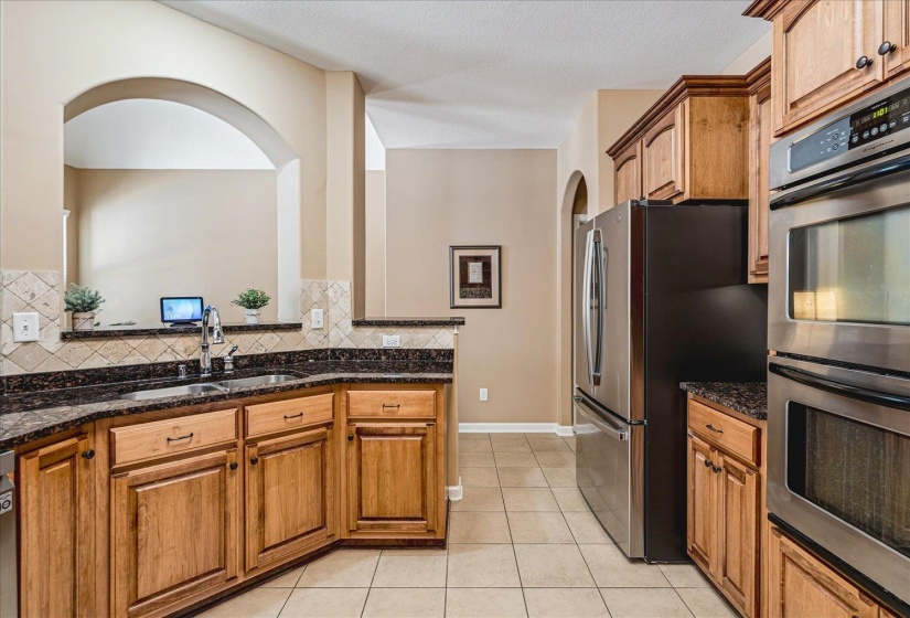 Kitchen featuring wood cabinetry, granite countertops, stainless steel appliances, and a tiled backsplash