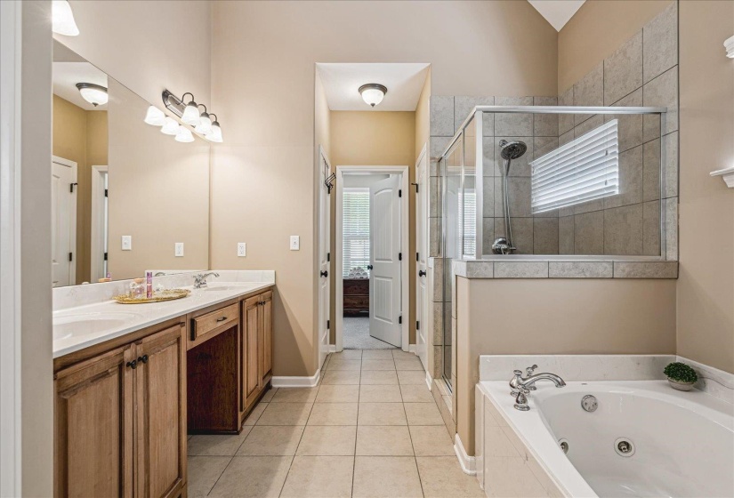 Neutral-toned bathroom featuring a dual-sink vanity with wood cabinetry and jetted tub and separate shower.