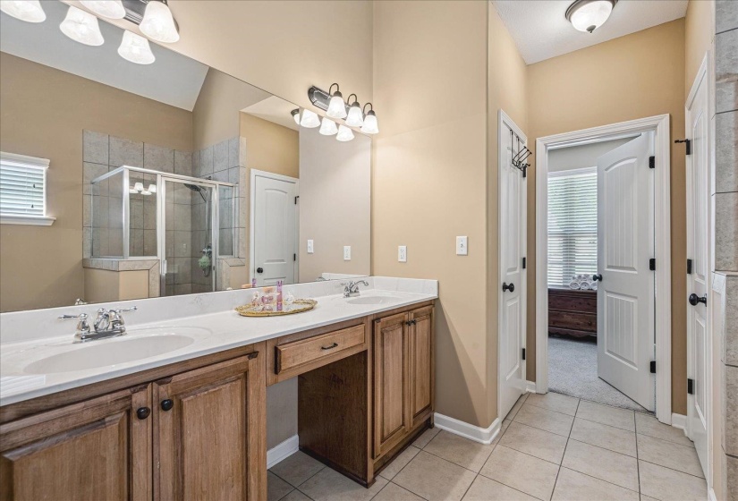 Neutral-toned bathroom featuring a dual-sink vanity with wood cabinetry and jetted tub and separate shower.
