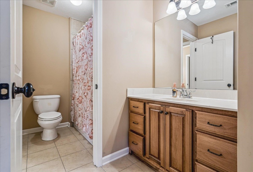 Bathroom featuring a wood-finish vanity with a white countertop, an integrated sink, and a large wall-mounted mirror. Full bath located on second story.