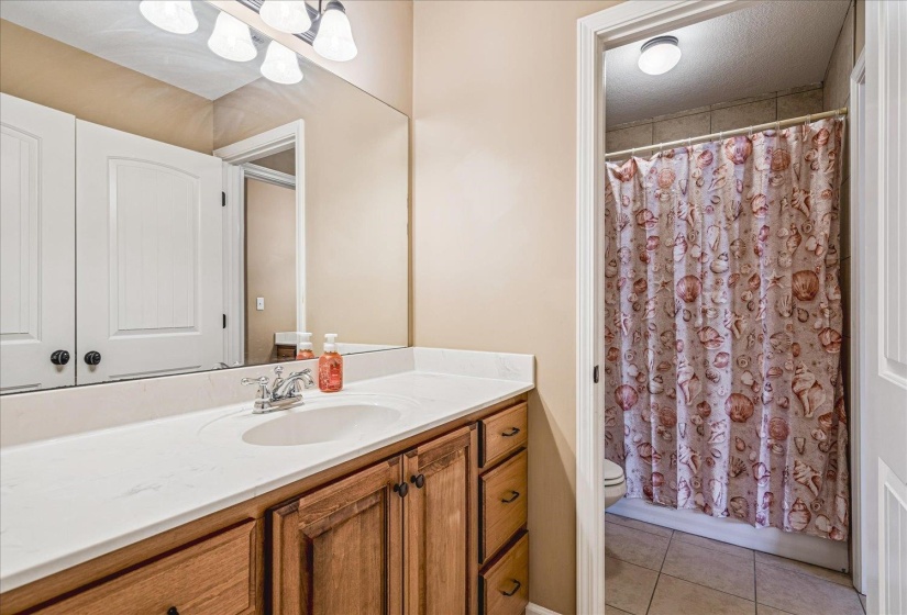 Bathroom vanity featuring a single basin, laminate countertop, and wood-finish cabinetry. Full bath located on second story.