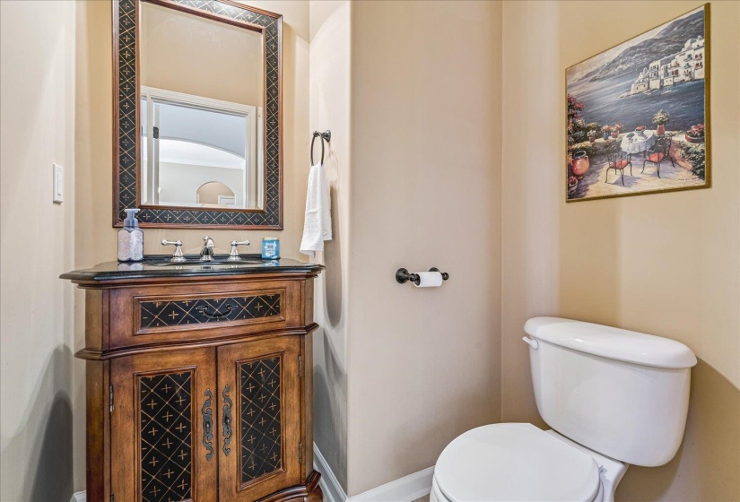 Bathroom with Ornate wood-finish vanity with a black countertop. Half Bath.