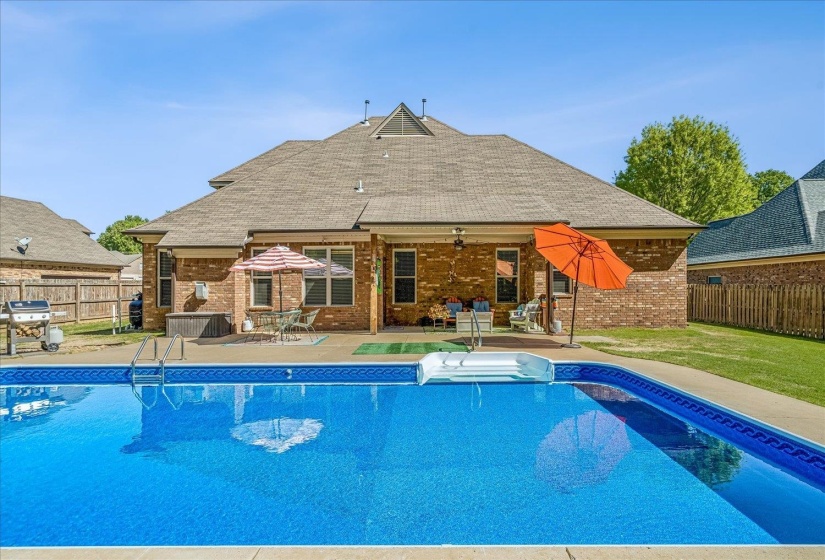 Expansive backyard featuring a rectangular in-ground swimming pool with integrated steps, a surrounding concrete patio, and a covered back patio. Salt Water System.New liner
