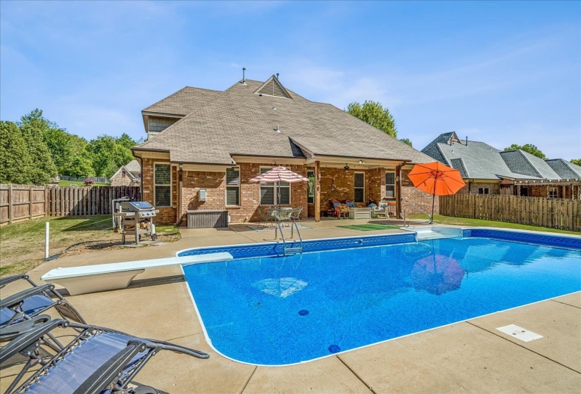 Expansive backyard featuring a rectangular in-ground swimming pool with integrated steps, a surrounding concrete patio, and a covered back patio. Salt Water System.New liner