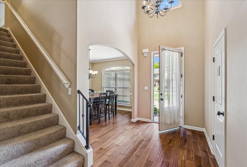 Two-story foyer featuring wood flooring, a decorative chandelier, and a transom window above the entry door