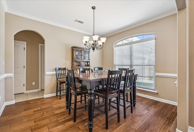 Formal Dining Room featuring wood flooring, a decorative arched doorway, and crown molding.