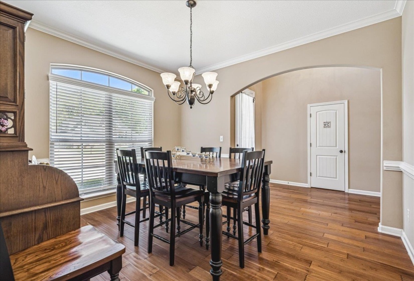 Formal Dining Room featuring wood flooring, a decorative arched doorway, and crown molding.