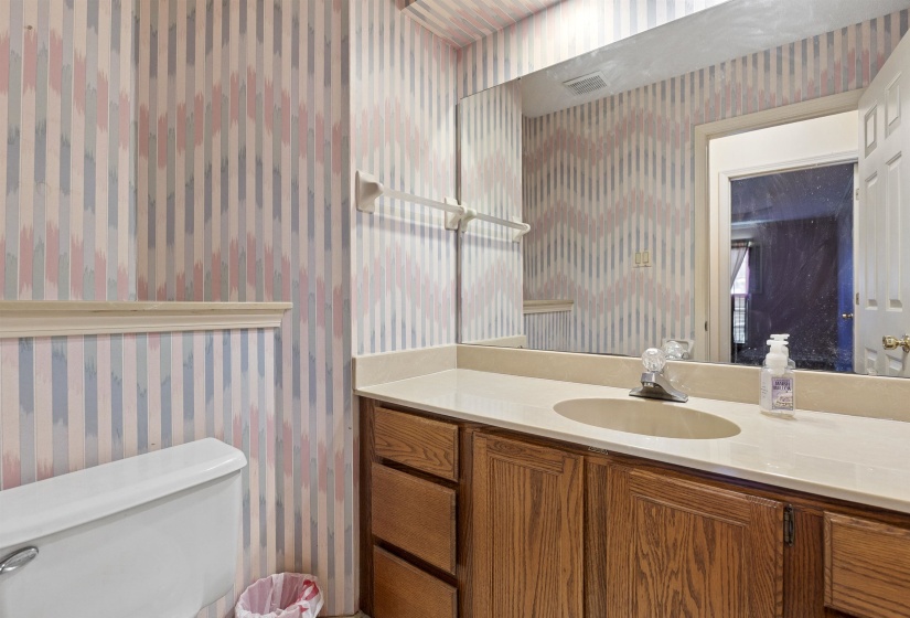 Vanity with an integrated sink, a large wall-mounted mirror, and an overhead light fixture