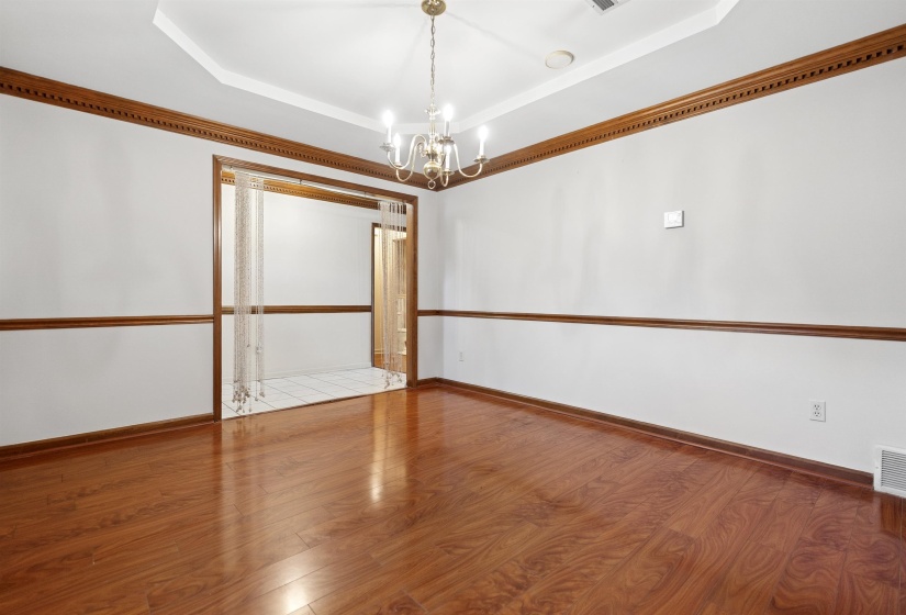 Spacious room featuring wood-finish flooring and a tray ceiling