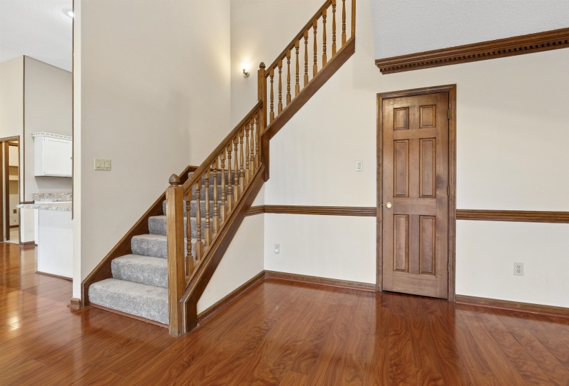 Staircase featuring wood balusters and carpeted treads, complemented by rich wood-finish flooring