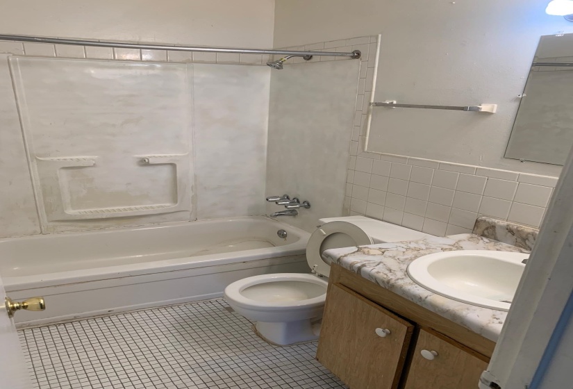 Bathroom with vanity, tile walls, light tile patterned floors, and shower / bath combination