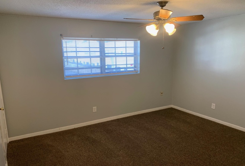 Spare room with dark carpet, a textured ceiling, and ceiling fan
