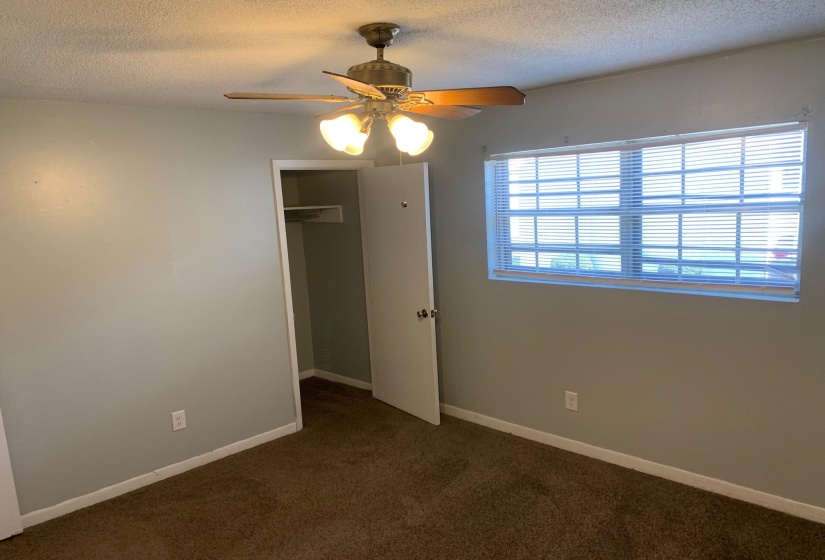 Unfurnished bedroom with dark carpet, a textured ceiling, ceiling fan, and a closet