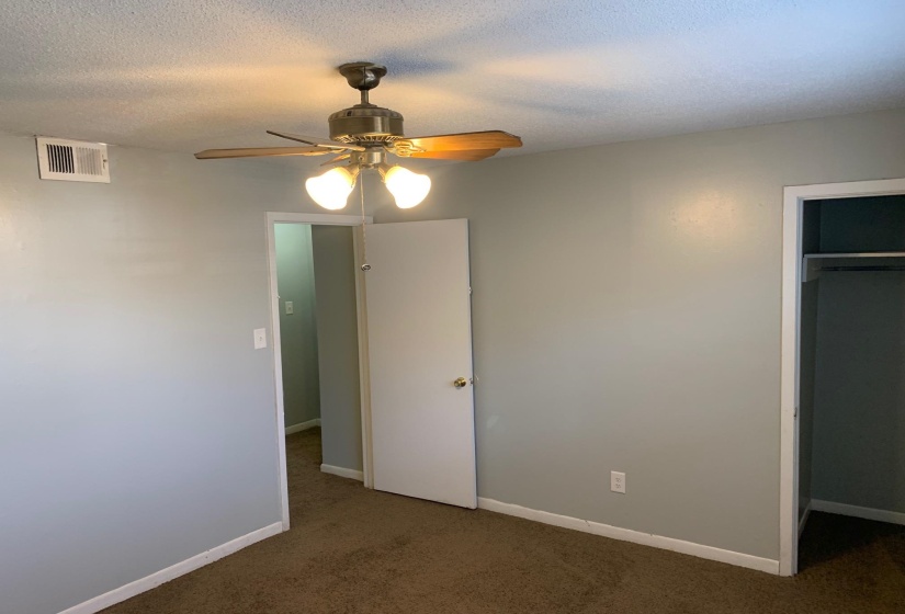 Unfurnished bedroom with carpet, a ceiling fan, a closet, and a textured ceiling