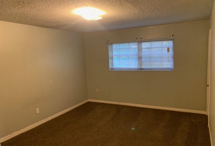 Carpeted empty room featuring a textured ceiling and baseboards