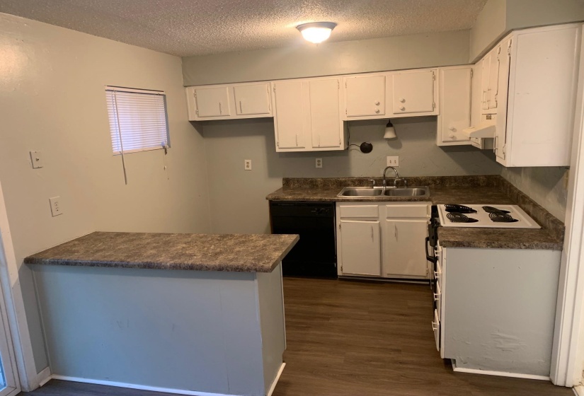Kitchen with dark countertops, white cabinets, white electric range oven, dishwasher, and a textured ceiling