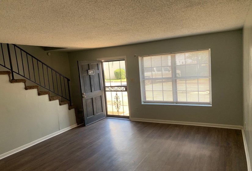 Foyer entrance featuring a textured ceiling, dark wood-type flooring, and stairs