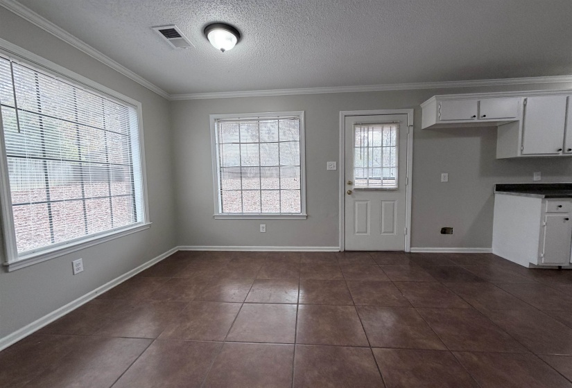 Kitchen with ornamental molding, a textured ceiling, white cabinets, dark tile patterned floors, and dark countertops