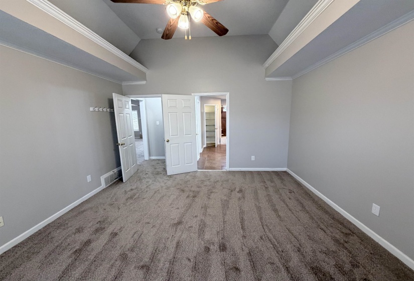 Unfurnished bedroom with crown molding, carpet floors, a ceiling fan, and high vaulted ceiling