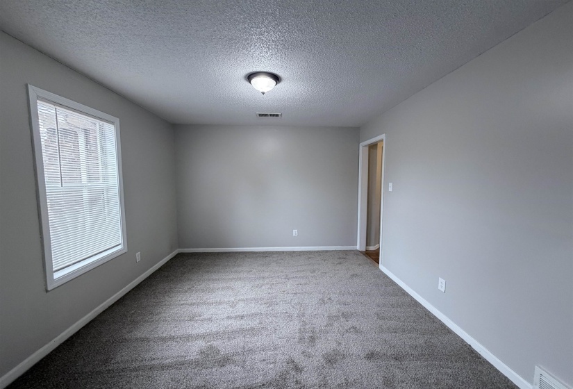 Unfurnished room featuring a textured ceiling and light carpet