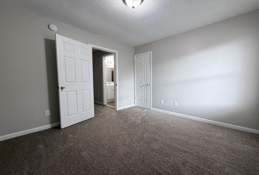 Unfurnished bedroom featuring a textured ceiling, dark carpet, and a closet