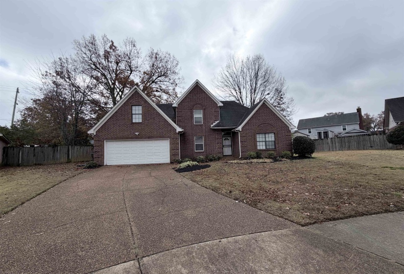 Traditional home featuring driveway, brick siding, and a garage