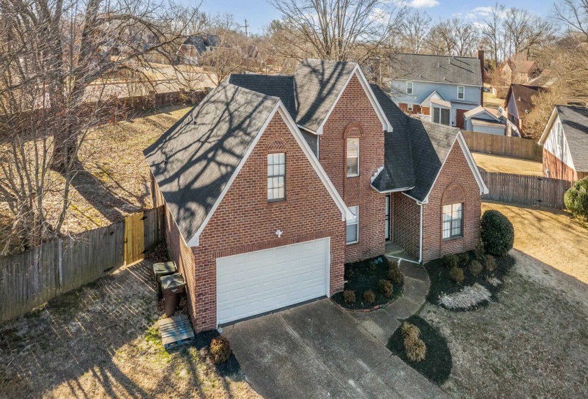 View of front facade with brick siding, a shingled roof, driveway, and an attached garage