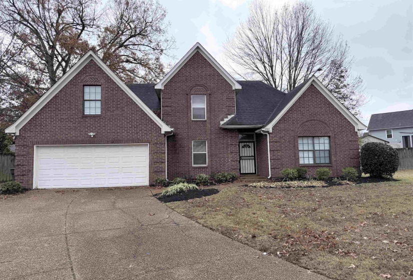 View of front of home with concrete driveway, a garage, and brick siding