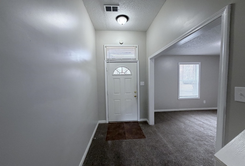 Foyer featuring a textured ceiling and dark carpet