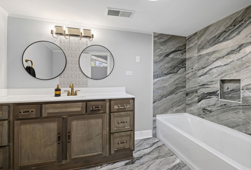Full bath with vanity, a bath, light marble finish floors, and ornamental molding