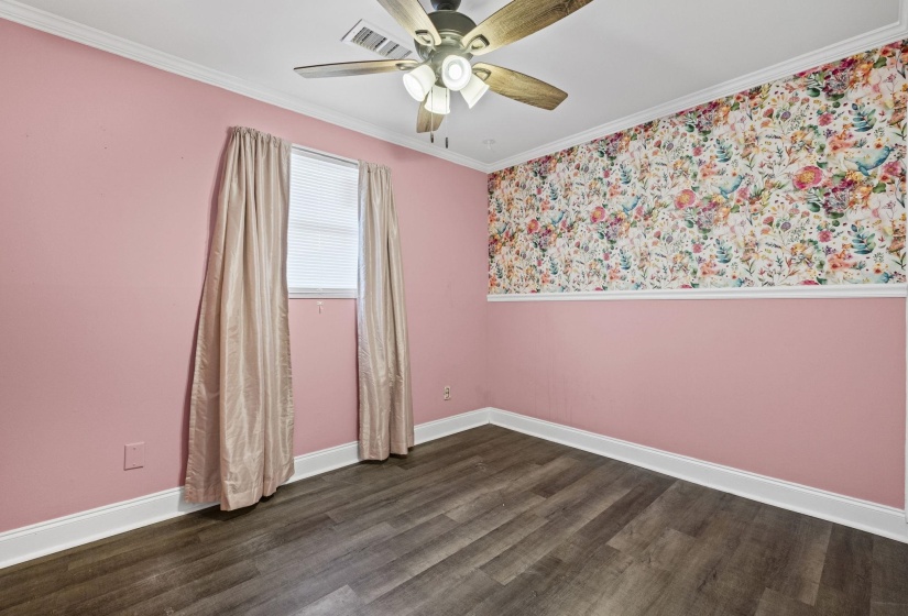Empty room featuring crown molding, dark wood finished floors, and a ceiling fan