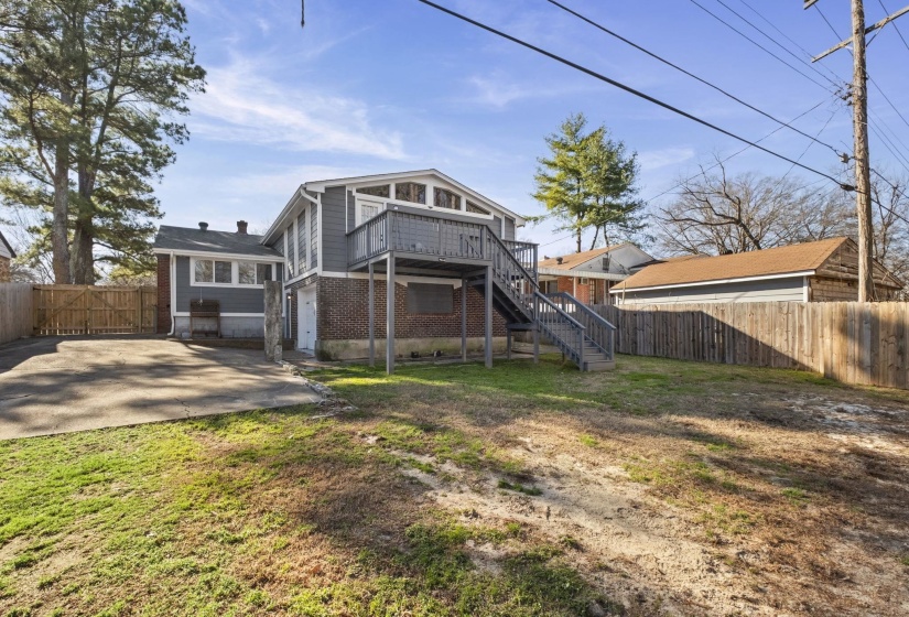 Rear view of house featuring stairs, a fenced backyard, a wooden deck, and brick siding