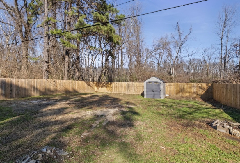 Fenced backyard featuring a storage unit