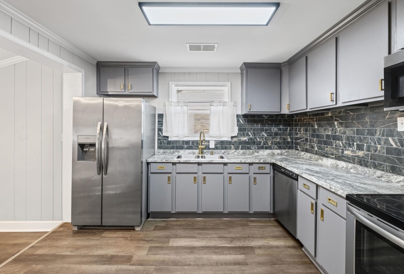 Kitchen with gray cabinets, appliances with stainless steel finishes, dark wood-type flooring, wooden walls, and decorative backsplash