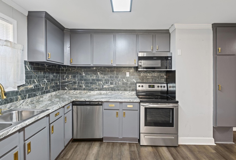 Kitchen with gray cabinets, stainless steel appliances, dark wood-style floors, backsplash, and crown molding