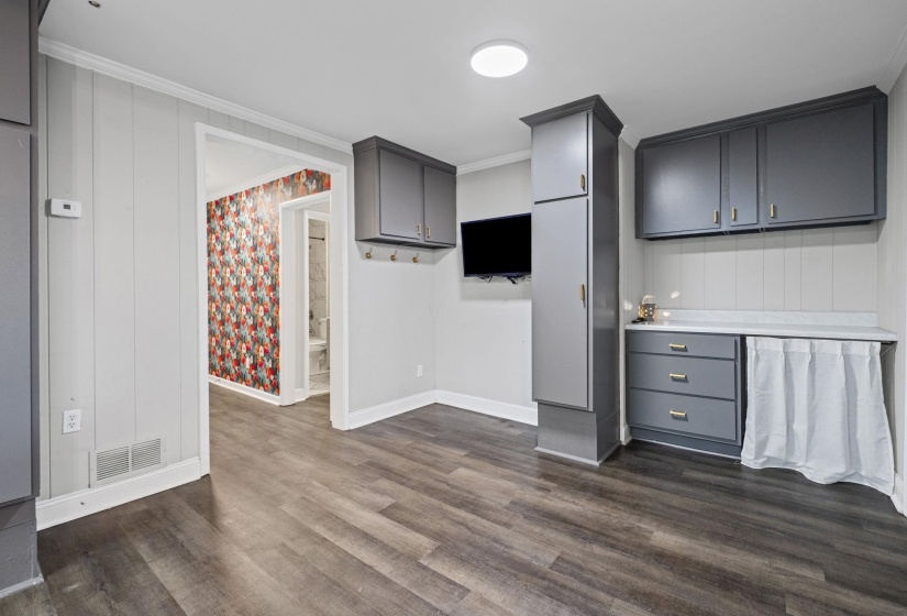 Kitchen featuring gray cabinetry, light countertops, ornamental molding, and dark wood-style flooring