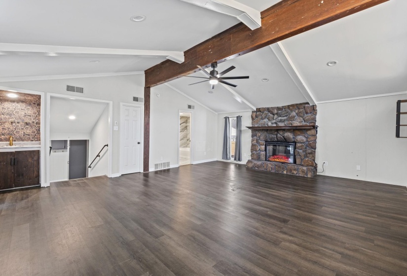 Unfurnished living room featuring dark wood-style flooring, a fireplace, and ceiling fan