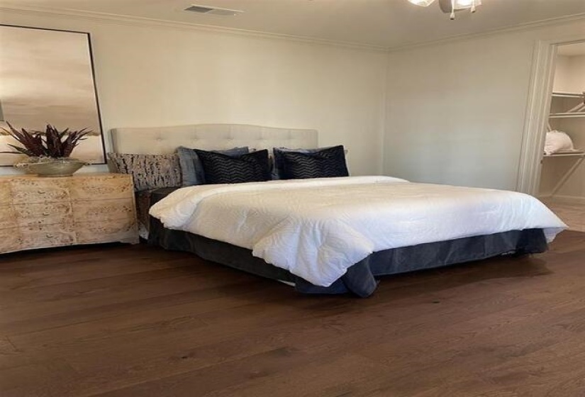 Room featuring crown molding, wood-finish flooring, a built-in closet with shelving, and a ceiling fan with light fixture