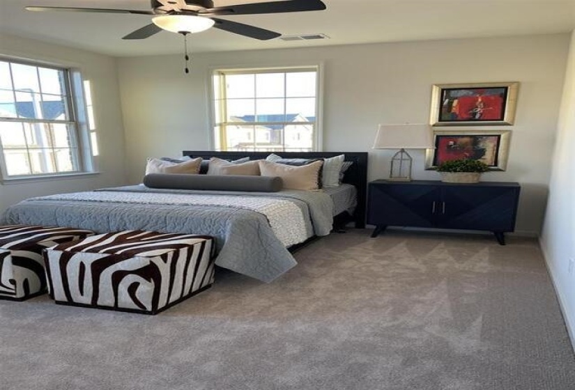 Carpeted bedroom featuring a ceiling fan with integrated lighting, two double-hung windows, a recessed lighting fixture, and light-toned wall paint