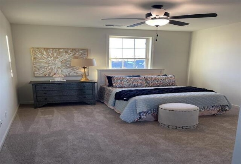 Carpeted bedroom featuring a large window, a ceiling fan with integrated lighting, and a white paneled headboard