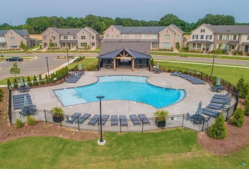 Resort-style pool area featuring a freeform swimming pool, extensive concrete deck, and black metal fencing
