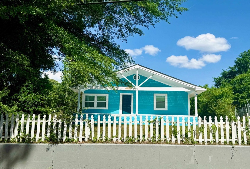 Vibrant turquoise exterior with white trim and a contrasting dark entry door