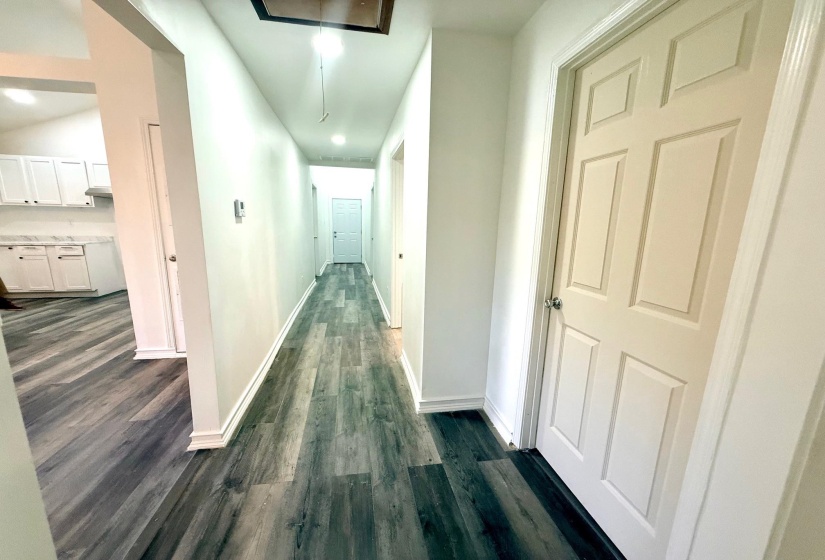 Hallway featuring wood-finish flooring, white baseboards, and white panel doors
