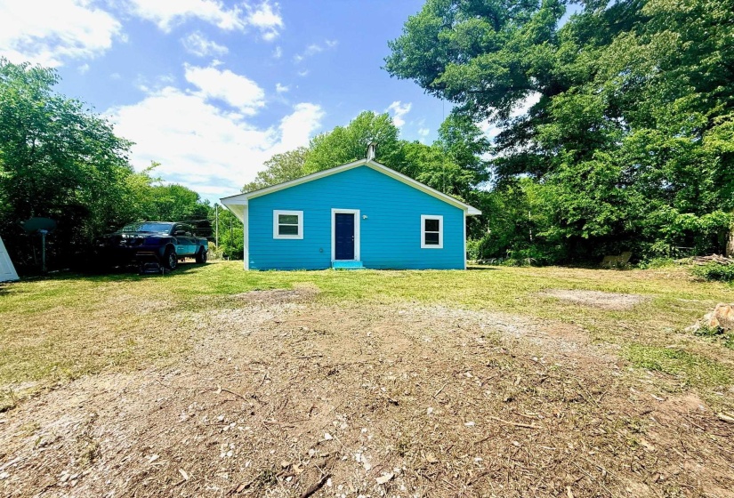 Single-story home featuring a vibrant blue exterior, a gabled roof, and white-framed windows