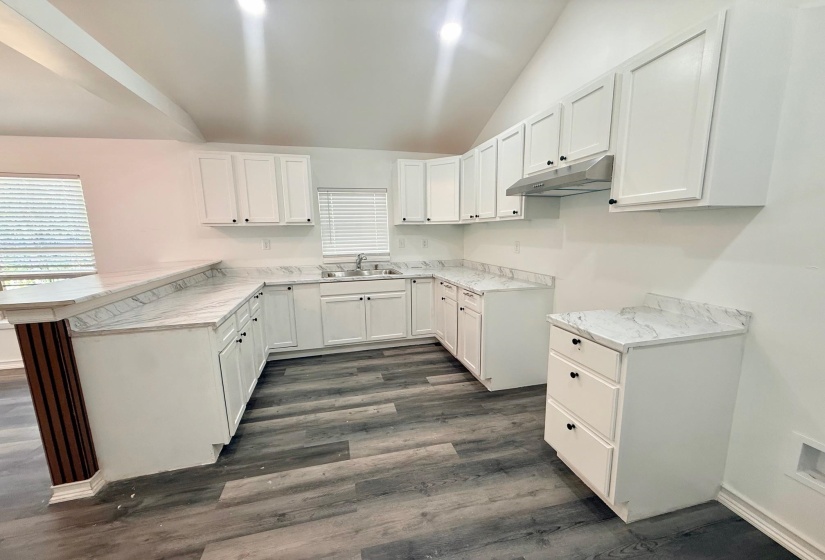 Modern kitchen featuring a vaulted ceiling and wood-finish flooring