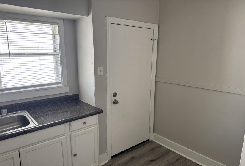 Kitchenette featuring a stainless steel sink, dark speckled countertop, and white cabinetry