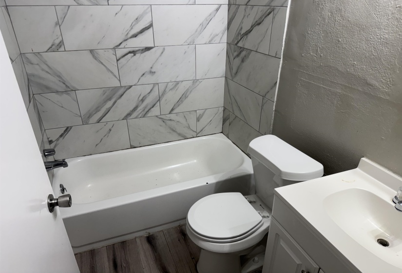 Bathroom featuring a white bathtub, toilet, and vanity with a single basin sink