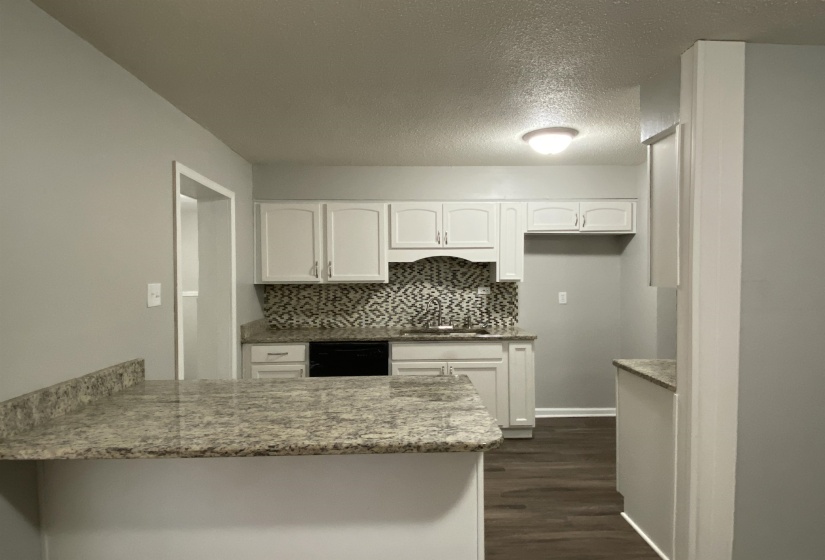 Kitchen with white cabinets, a peninsula, decorative backsplash, dark wood-style flooring, and a textured ceiling